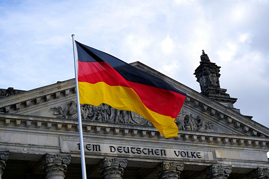 German national flag waving in front of the Reichstag building in Berlin, a symbol of democracy.