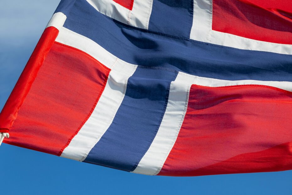 Close-up of Norwegian flag with vibrant red, white, and blue colors against a clear sky.