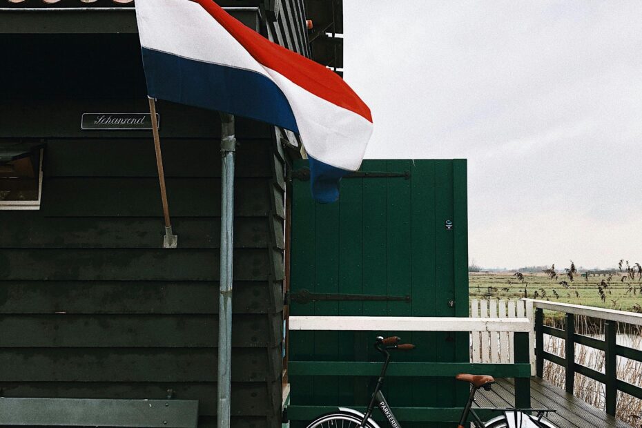 A classic Dutch scene featuring a bicycle and flag by a traditional Zaandam wooden house.