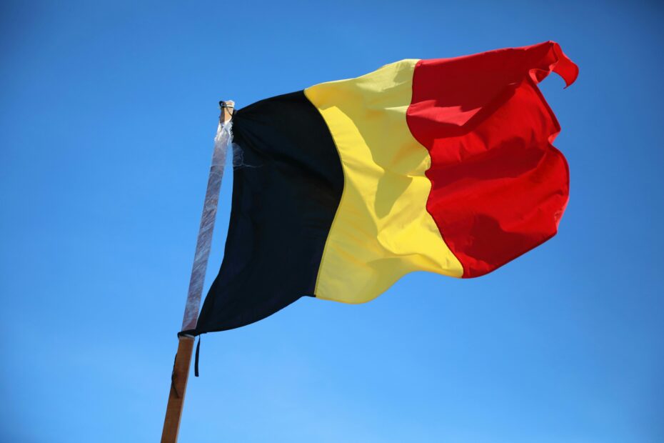 Vibrant Belgium flag against clear blue sky, symbolizing national pride and patriotism.