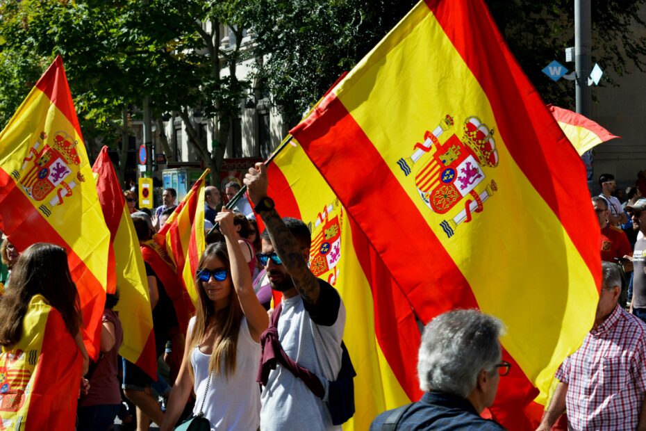 Vibrant street rally in Barcelona with people waving Spanish flags, capturing a lively outdoor atmosphere.