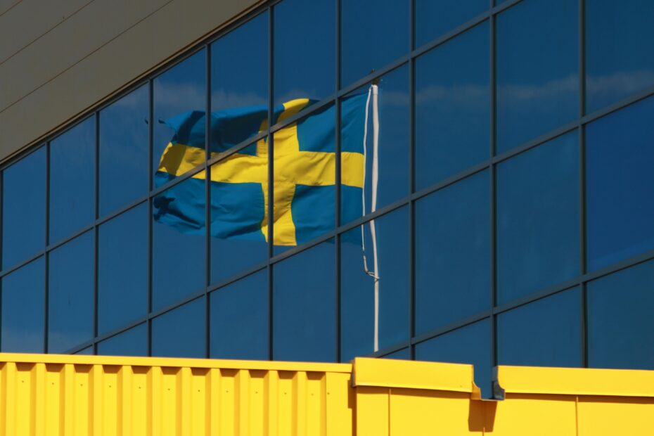 A Swedish flag reflected in glass windows of a modern building in Jönköping, Sweden.