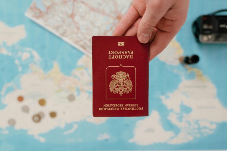 A hand holding a Russian passport over a map, suggesting travel preparation.